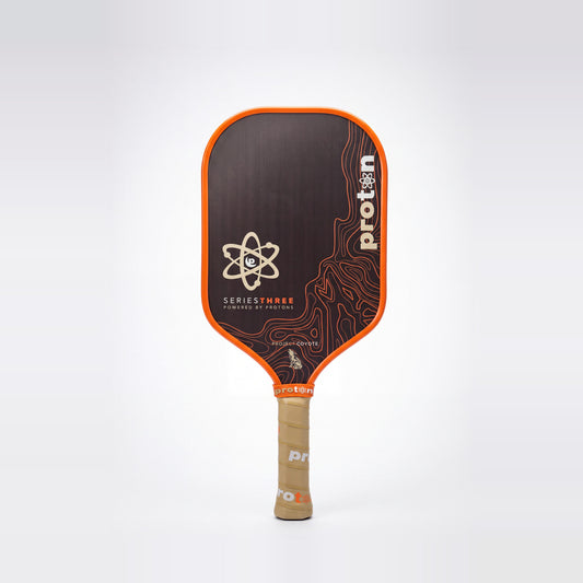 Proton Project Coyote Elongated 15mm pickleball paddle — front face, orange edge guard and tan grip